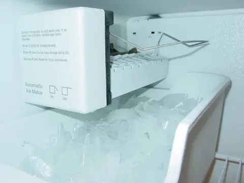 Automatic ice maker inside a refrigerator freezer with a bin of ice cubes