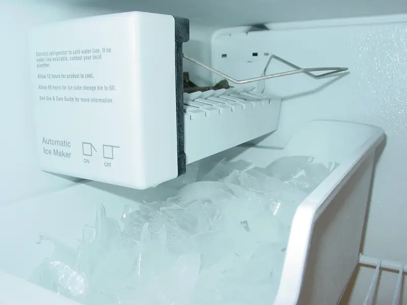 Refrigerator ice maker with a bin of ice cubes, showing the cube size an ice maker repair aims to restore